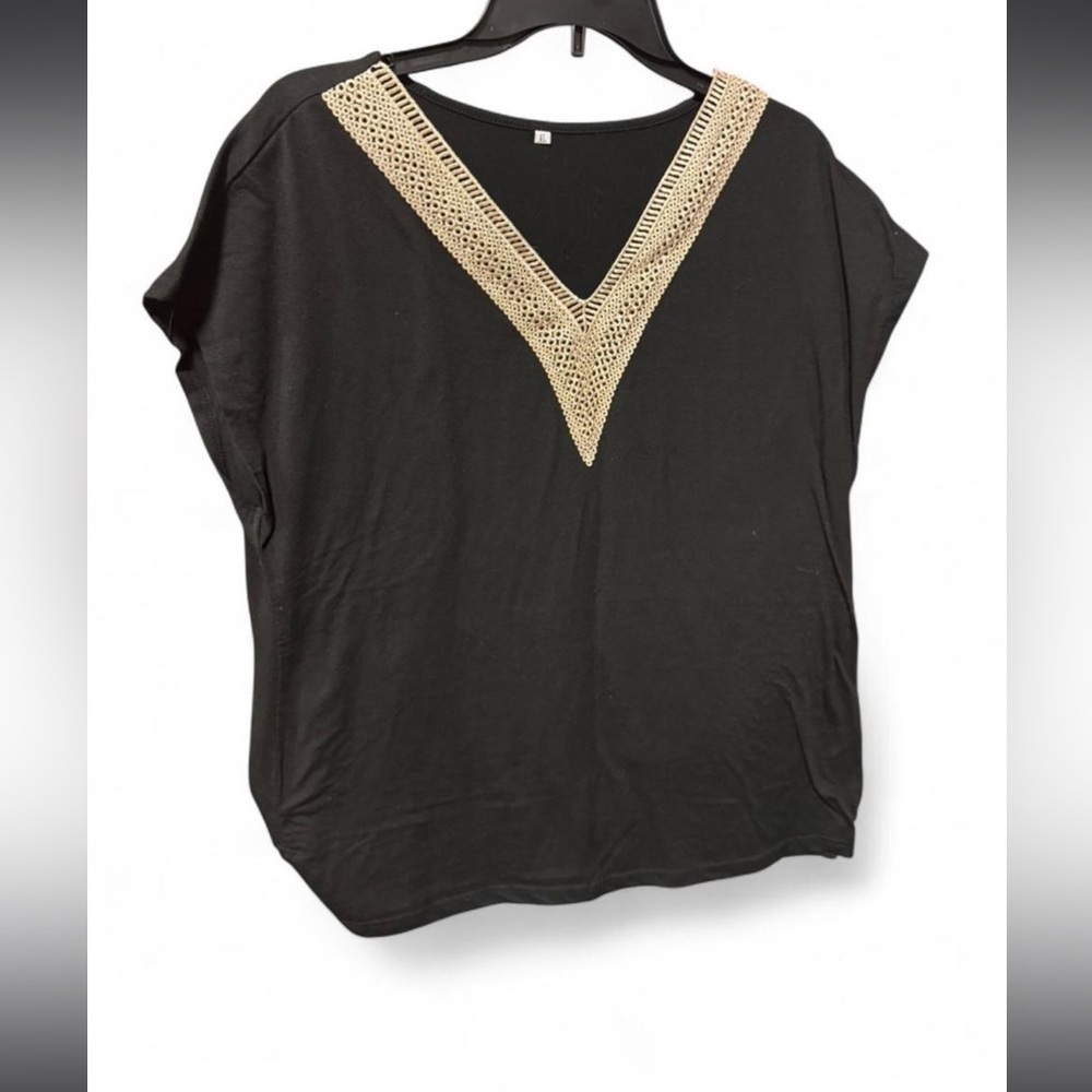 Black blouse features a v-neckline adorned with beige crochet or lace accent